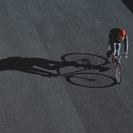 Cyclist is crossing the road and dropping beautiful shadow